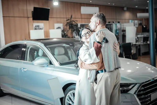 Amante atraente esposa abraçando seu marido depois de receber o carro — Fotografia de Stock