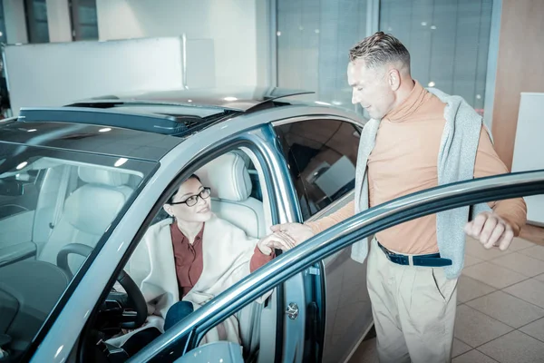 Caring loving man giving hand to his woman leaving car