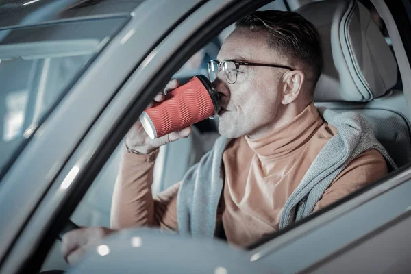 Şık işadamı araba sürüş sırasında kahve içme