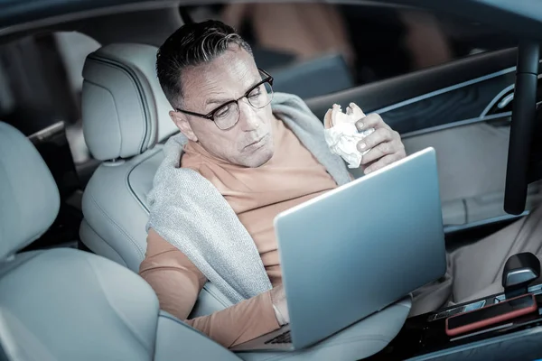 Занятой бизнесмен ест бургеры и работает на ноутбуке — стоковое фото