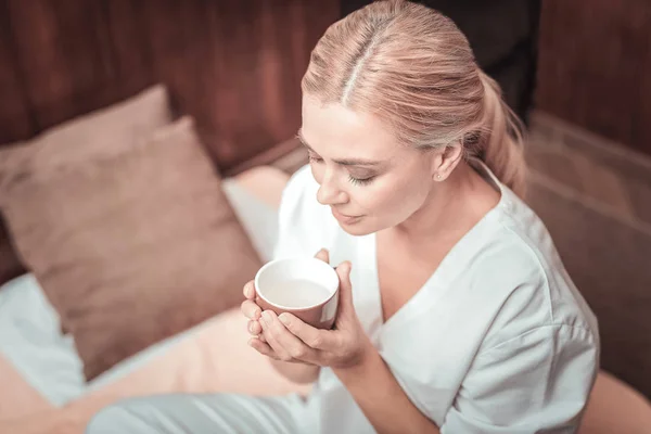 Trevlig blond kvinna tittar på koppen — Stockfoto