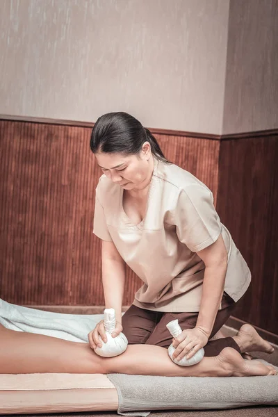 Серьёзный массажист, использующий сумки для массажа ног — стоковое фото