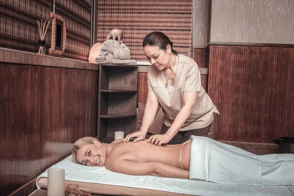 Alegre agradable mujer teniendo un masaje de piedra —  Fotos de Stock