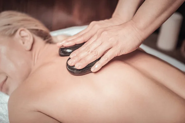 Niza masajista experto utilizando piedras calientes para el masaje —  Fotos de Stock