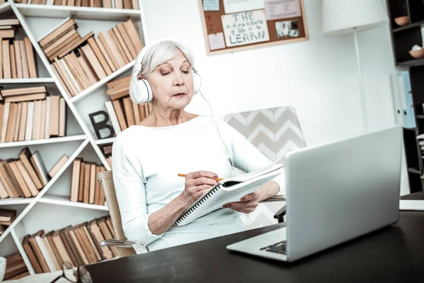 Attentive senior teacher doing listening task in headphones — Stock Photo, Image