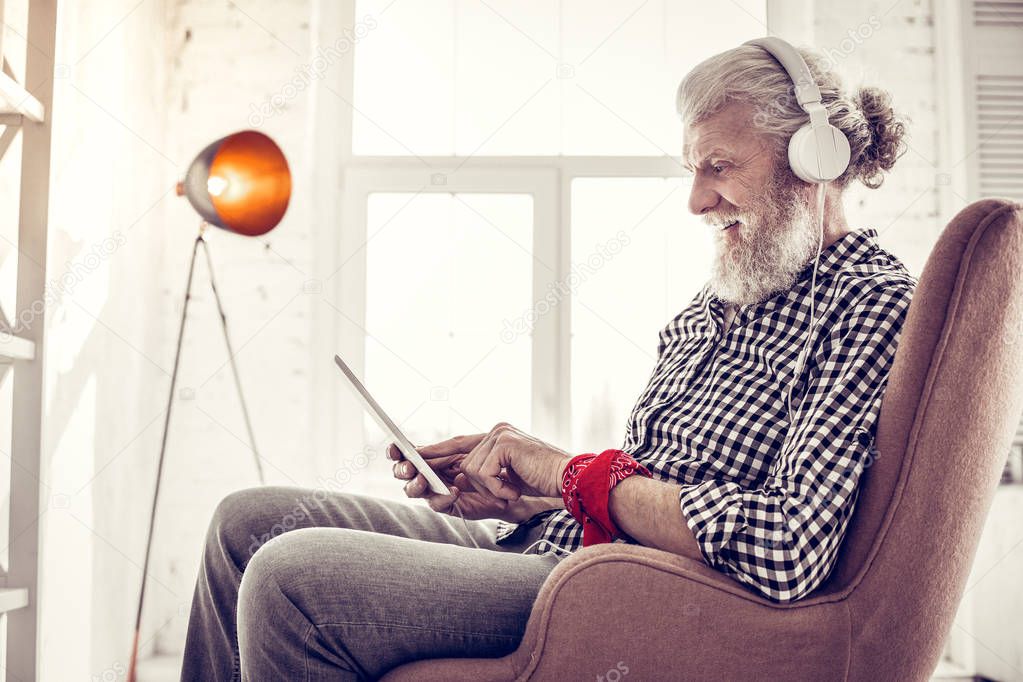Pleased elderly male person staring at his gadget