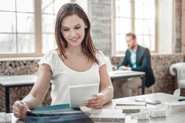 Küçük beyaz tablet tutan yetenekli yaratıcı moda tasarımcısı