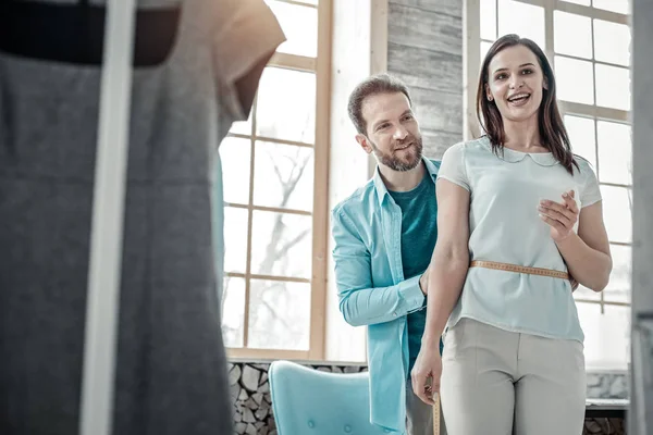 Esposo trabajando como diseñador de moda midiendo la cintura de la esposa — Foto de Stock