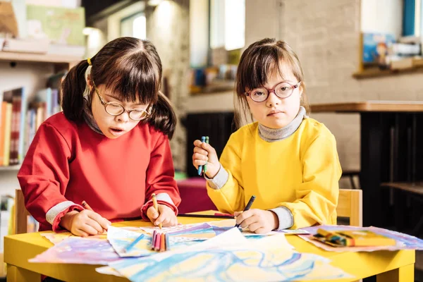 Two girls with congenital acromicria wearing glasses drawing together — Stock Photo, Image