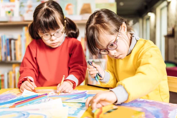 Sisters having Down syndrome feeling involved in coloring pictures — Stock Photo, Image