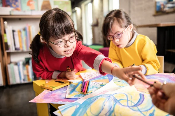 Girl having Down syndrome taking colorful marker from her teacher — Stock Photo, Image