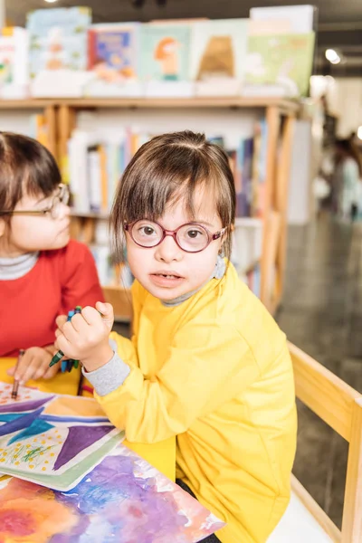 Jolie fille aux yeux foncés avec le syndrome de Down portant un pull jaune vif — Photo