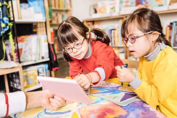 Dark-haired preschool girls with Down syndrome having drawing class