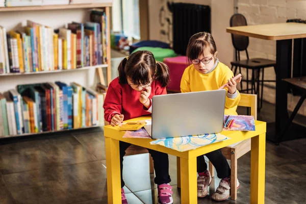 Two sisters with genetic disorder watching cartoon on laptop