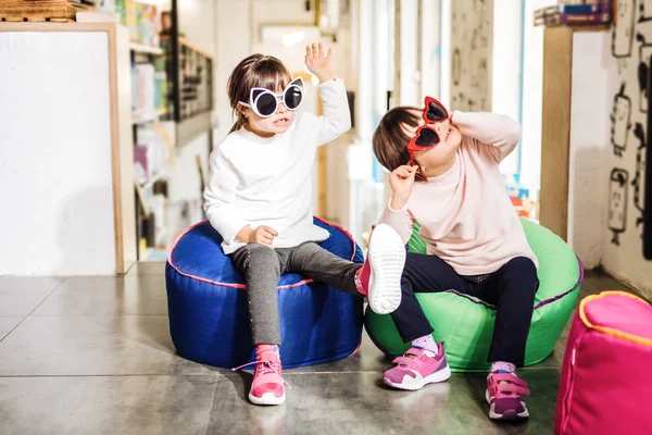 Gemelos con zapatillas de deporte de color rosa brillante y gafas de sol divertidas — Foto de Stock