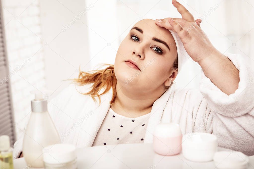 Plus-size peaceful woman spending her morning in bathroom