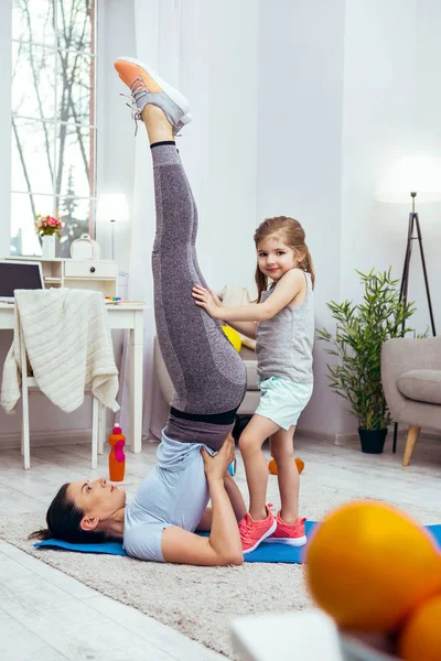 Glada vackra flicka håller benen mödrar — Stockfoto