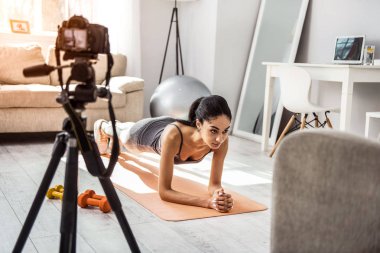 Ev egzersizleri fotoğraf makinesinde gösteren sportif genç eğitmeni