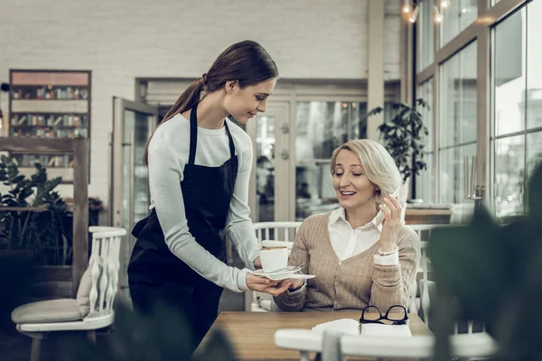 Обращаясь к темноволосой официантке, приносящей кофе своему клиенту — стоковое фото