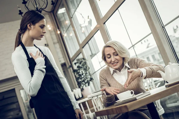 Жінка сперечається з офіціанткою, побачивши комарів у каві — стокове фото