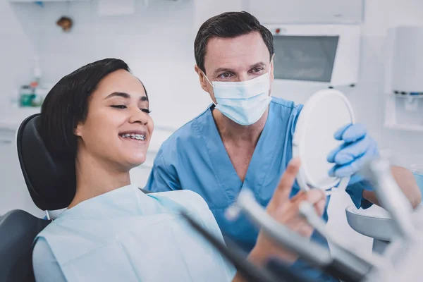 Glückliche junge Patientin überprüft ihre Zähne in der Klinik — Stockfoto