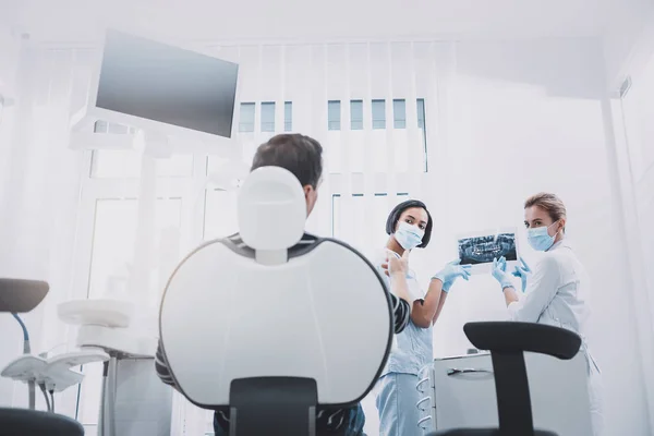 Paciente atento ouvindo seu dentista e assistente — Fotografia de Stock