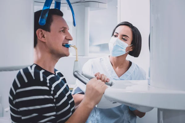 Dentista morena grave olhando para seu paciente — Fotografia de Stock