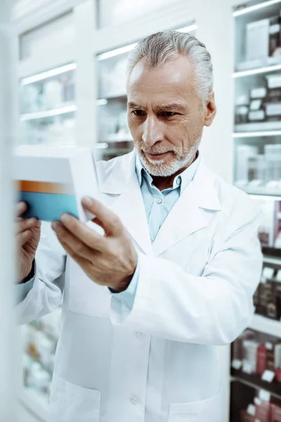 Koncentrovaná zralý muž kontrola léku před prodejem — Stock fotografie