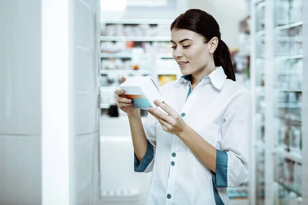 Радостная молодая продавщица, проверяющая качество медицины — стоковое фото