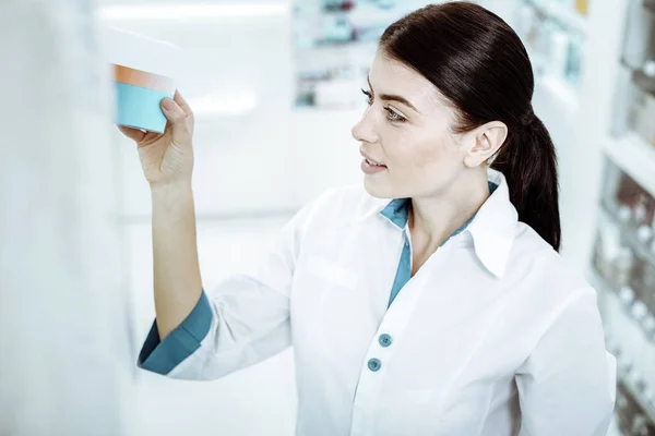 Attentive pharmacist looking at medicine on shelves — Stock Photo, Image
