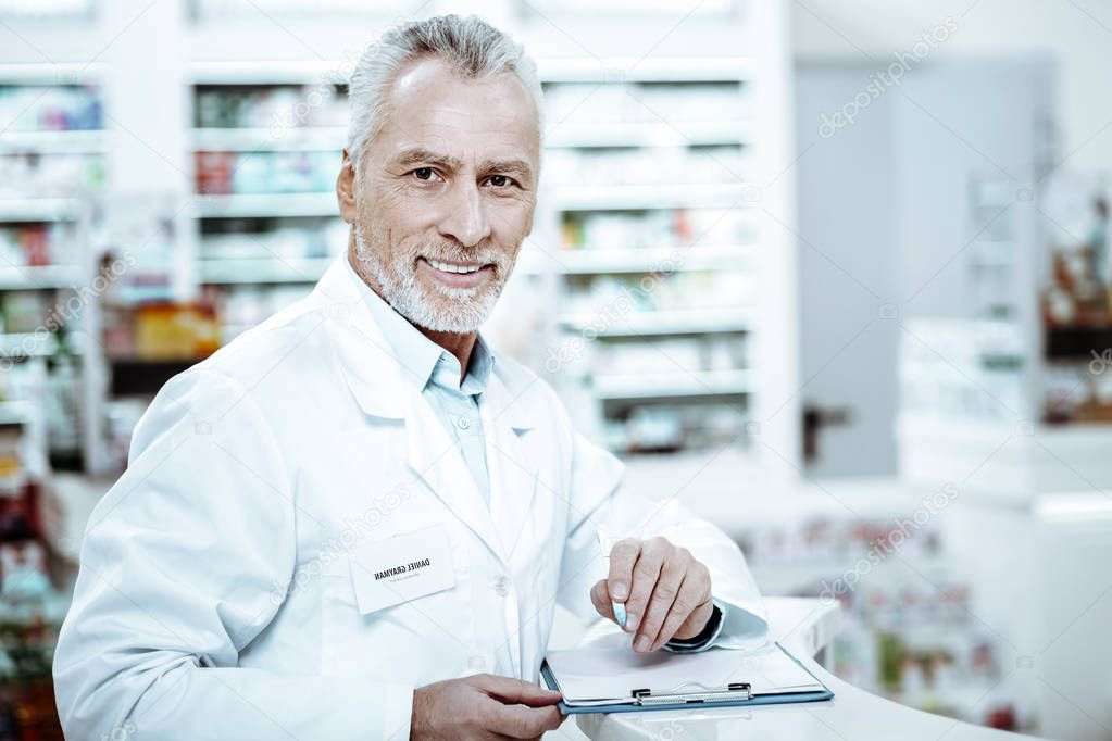 Cheerful bearded man making notes on documents