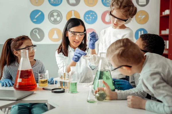 Joven científica competente enseñando a sus alumnos encantados — Foto de Stock