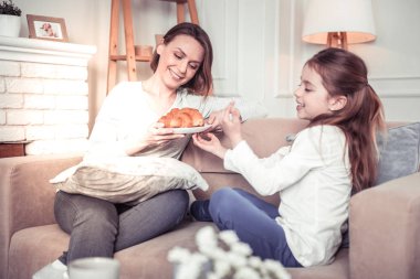 Delighted cheerful girl having breakfast with her mother