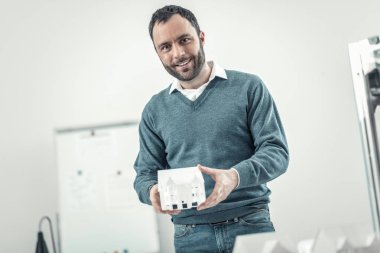Cheerful nice man holding a house model clipart