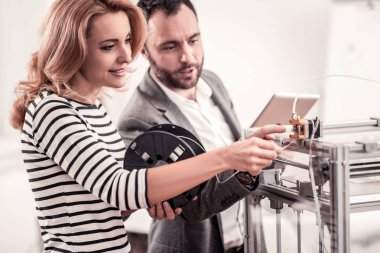 Nice woman asking her colleague about 3D printer