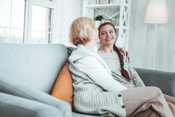 Радостная счастливая девушка и ее бабушка сидят на диване — стоковое фото