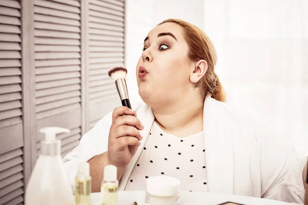 Body positive ginger lady blowing on her powder brush — Stock Photo, Image