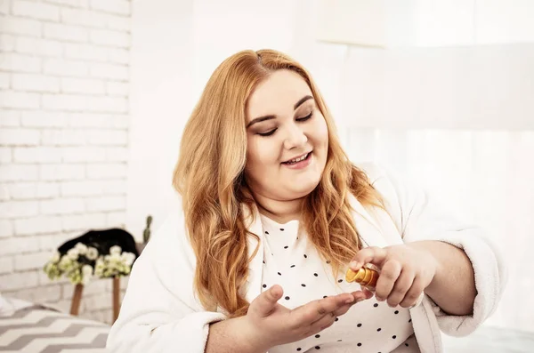 Contenta de pelo largo cuerpo positivo mujer apretando aceite para el cabello — Foto de Stock