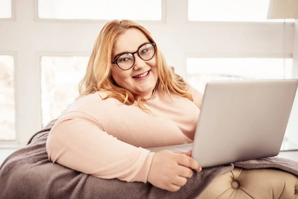 Souriante femme aux cheveux longs se détendre sur son canapé confortable — Photo