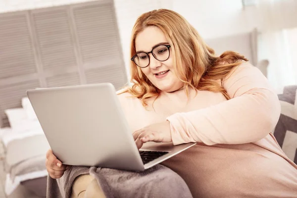 Långhårig kropp positiv koncentrerad kvinna som tittar på skärmen på laptop — Stockfoto