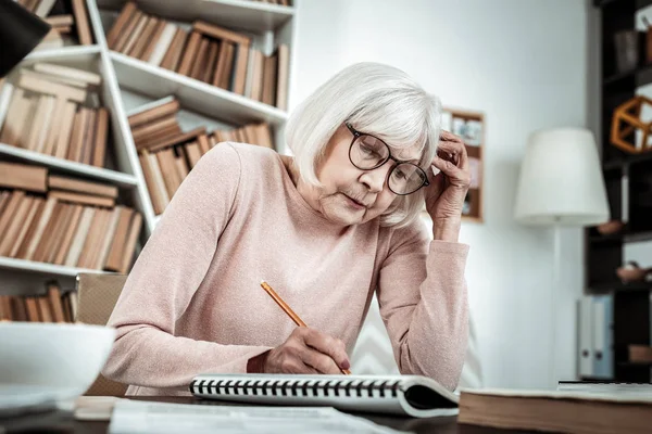 Concentrated senior female preparing task for lesson — Stock Photo, Image