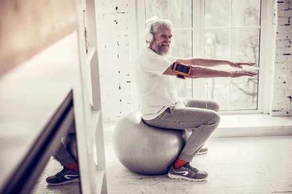 Reifer Mann sitzt auf Fitnessball im Fitnessstudio — Stockfoto