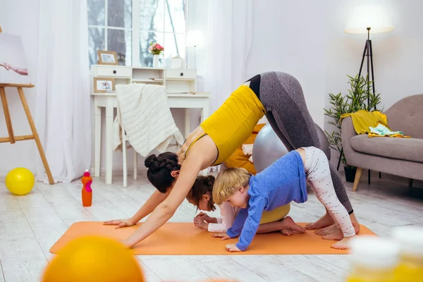 Mujer joven positiva haciendo ejercicio con sus hijos —  Fotos de Stock
