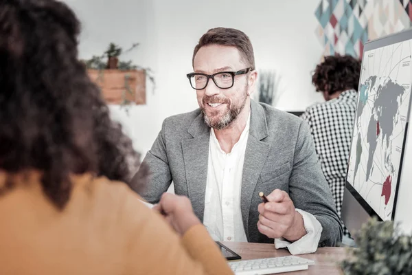 Cheerful office worker talking to his colleague