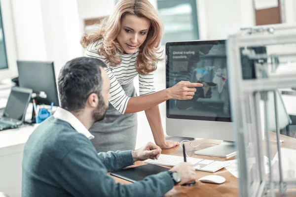 Mulher loira agradável apontando para a tela do computador — Fotografia de Stock