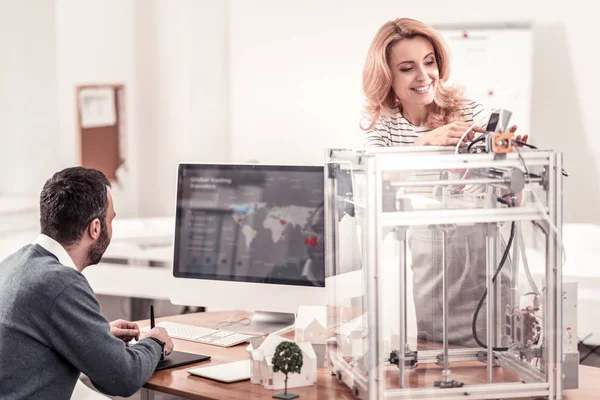 Smiling woman adjusting 3D printer at the office — Stok fotoğraf