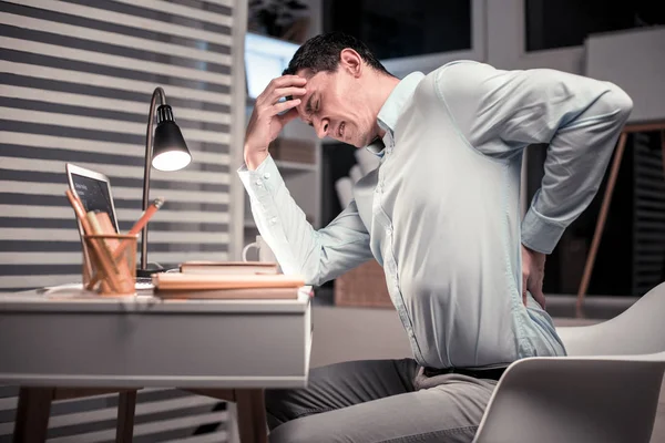 Ongezellig goed uitziende man aanraken van zijn rug — Stockfoto