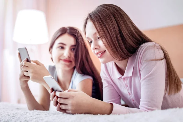 Glad two girls messaging with their phones — Stock Photo, Image