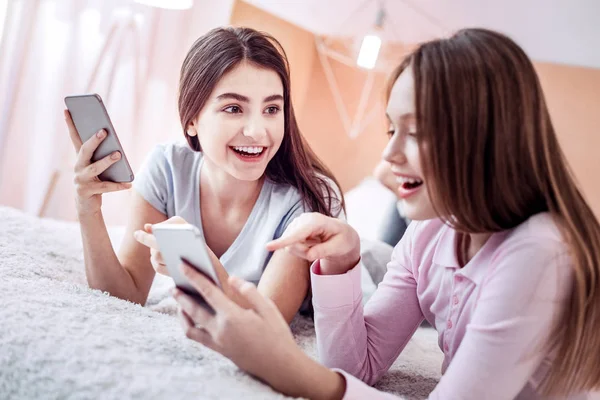 Sprudlande glada två tjejer granskar vänner foto — Stockfoto