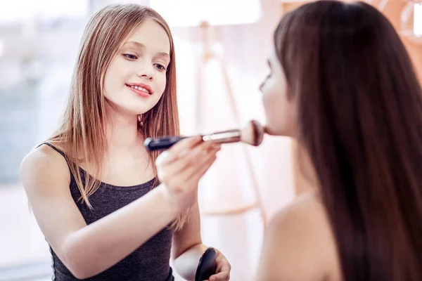 Peaceful two girls patting foundation before party